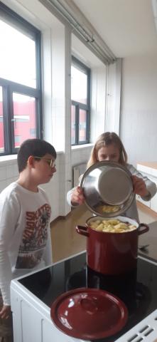 Zwei Kinder kochen Apfelkompott